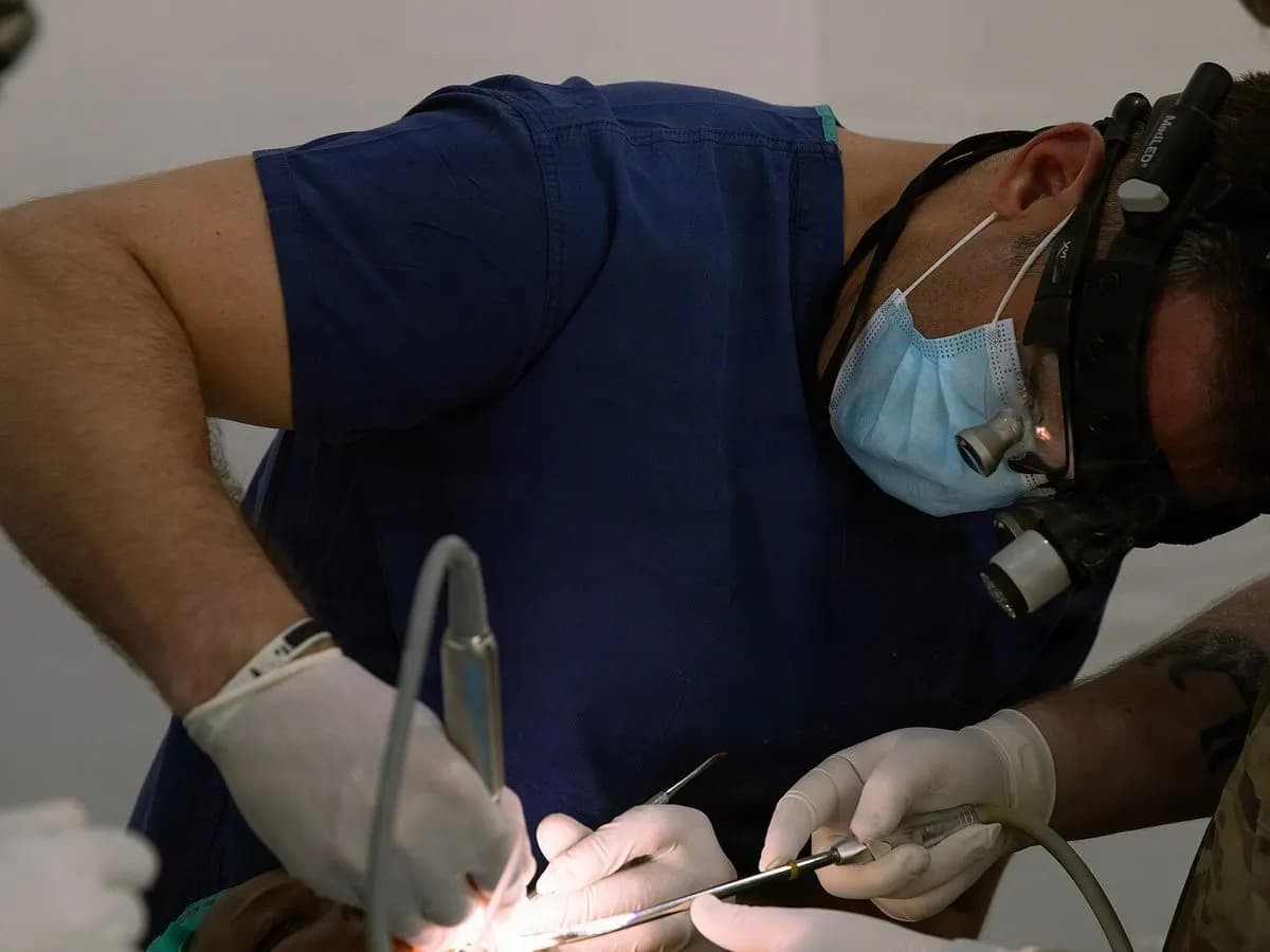 Chirurgien oral posant un implant dentaire, loupes et lampe frontale