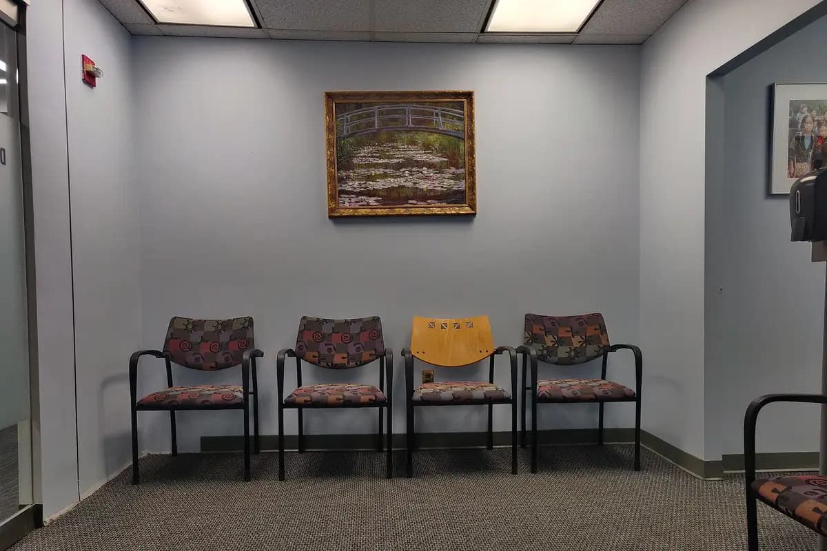 Salle d'attente d'un cabinet médical, chaises alignées sous un tableau